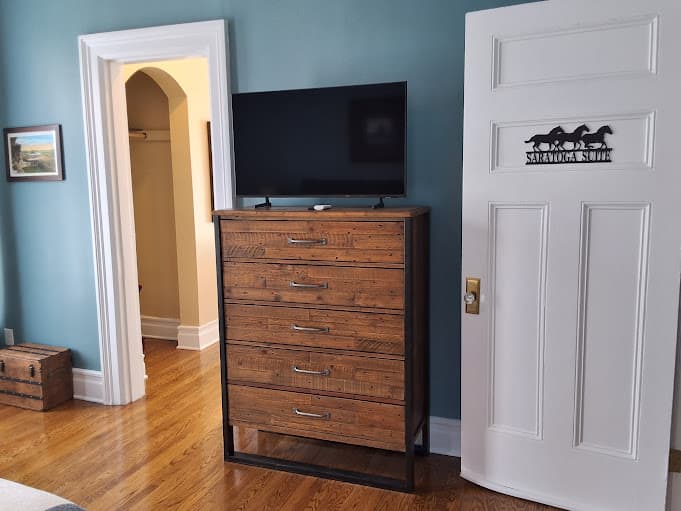 A wood and metal dresser topped with a flat-screen TV.
