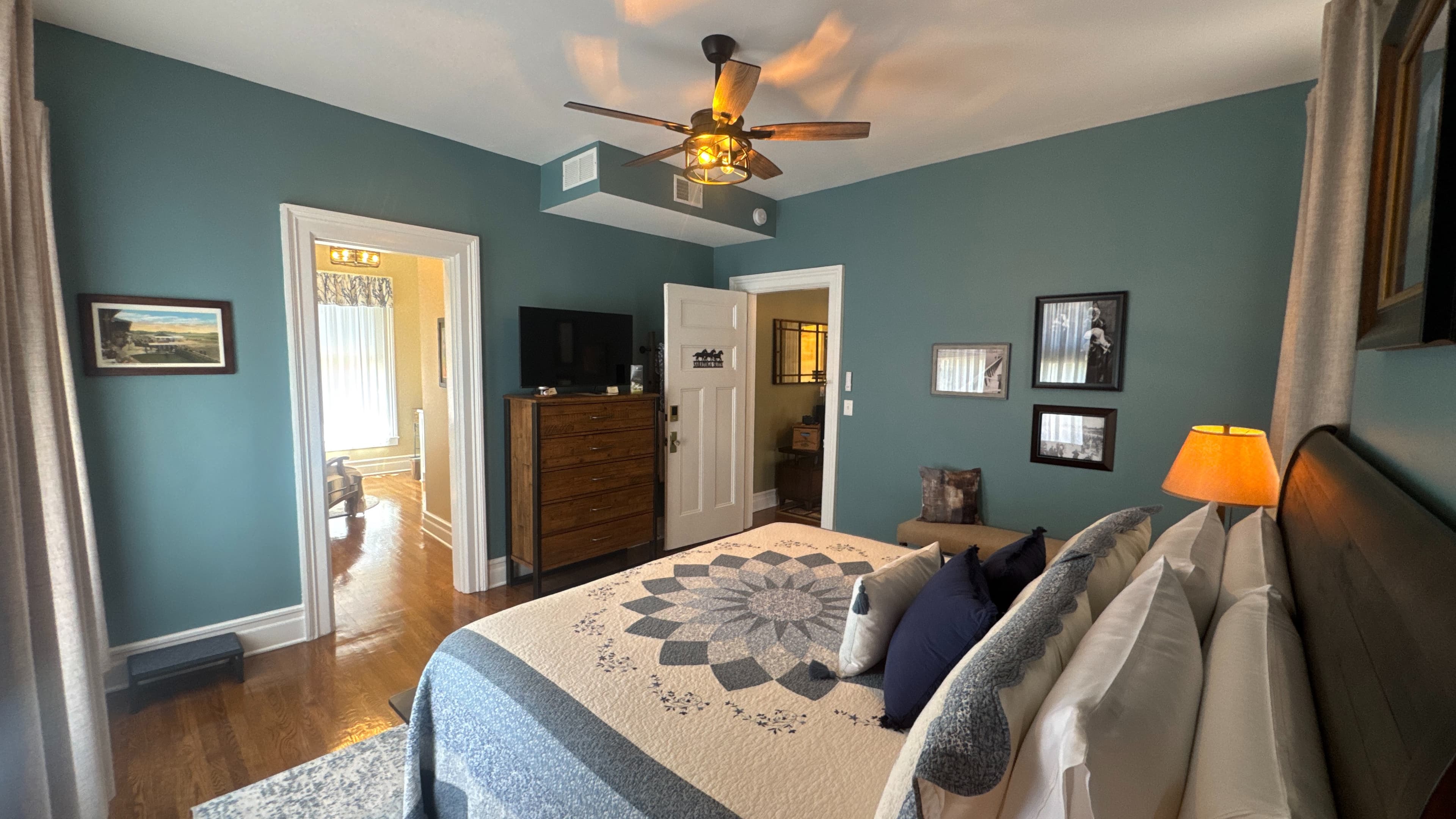 An inviting king-size bed topped with a beautiful quilt and flanked by nightstands with lamps.