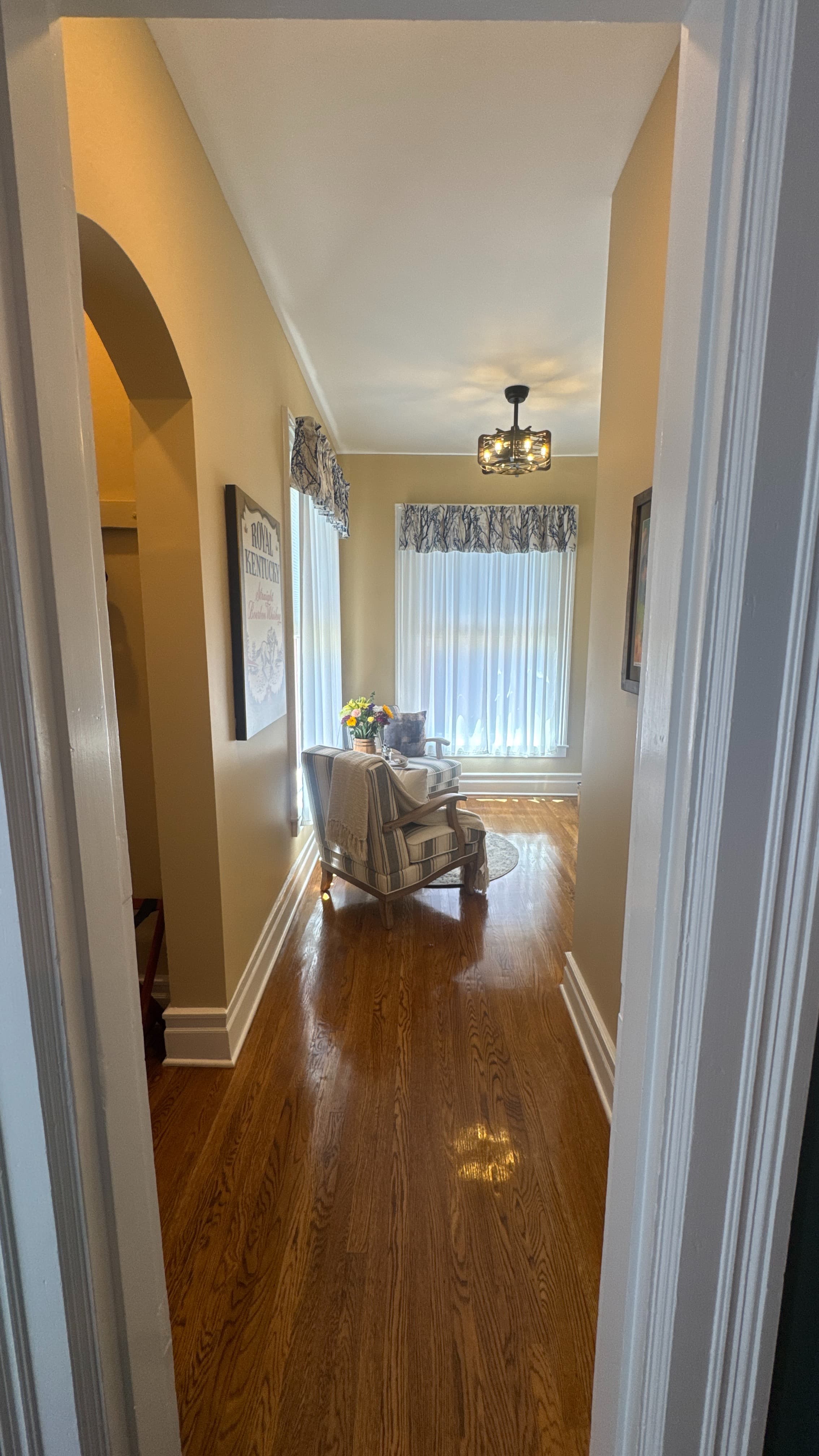 Sitting area with end table flanked by upholstered chairs in front of a window with white sheer curtain.
