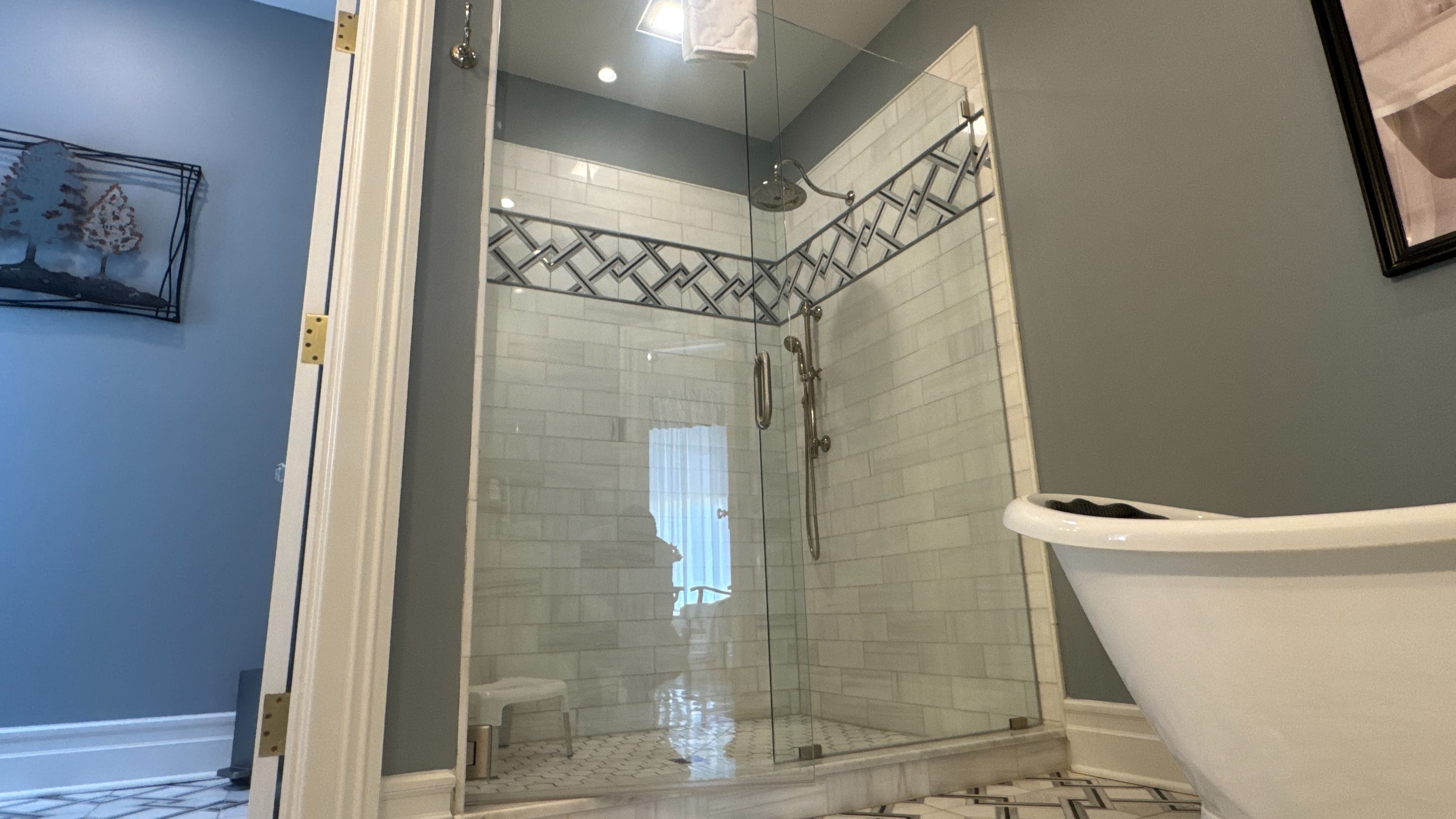 Spacious bathroom with glass-enclosed tiled shower and soaking slipper tub.