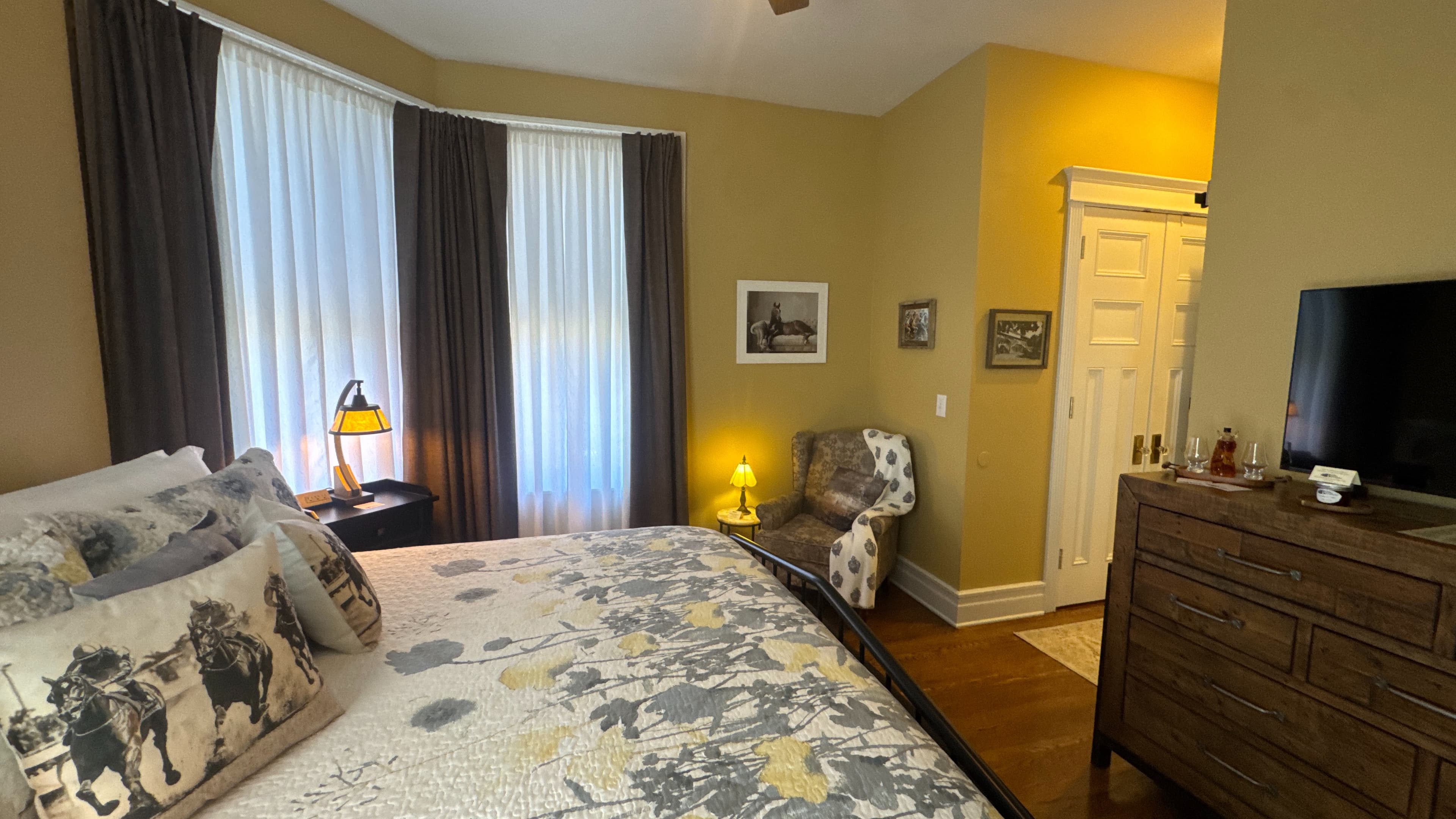 Wooden dresser topped with flat-screen TV next to wall opposite the king-size bed.