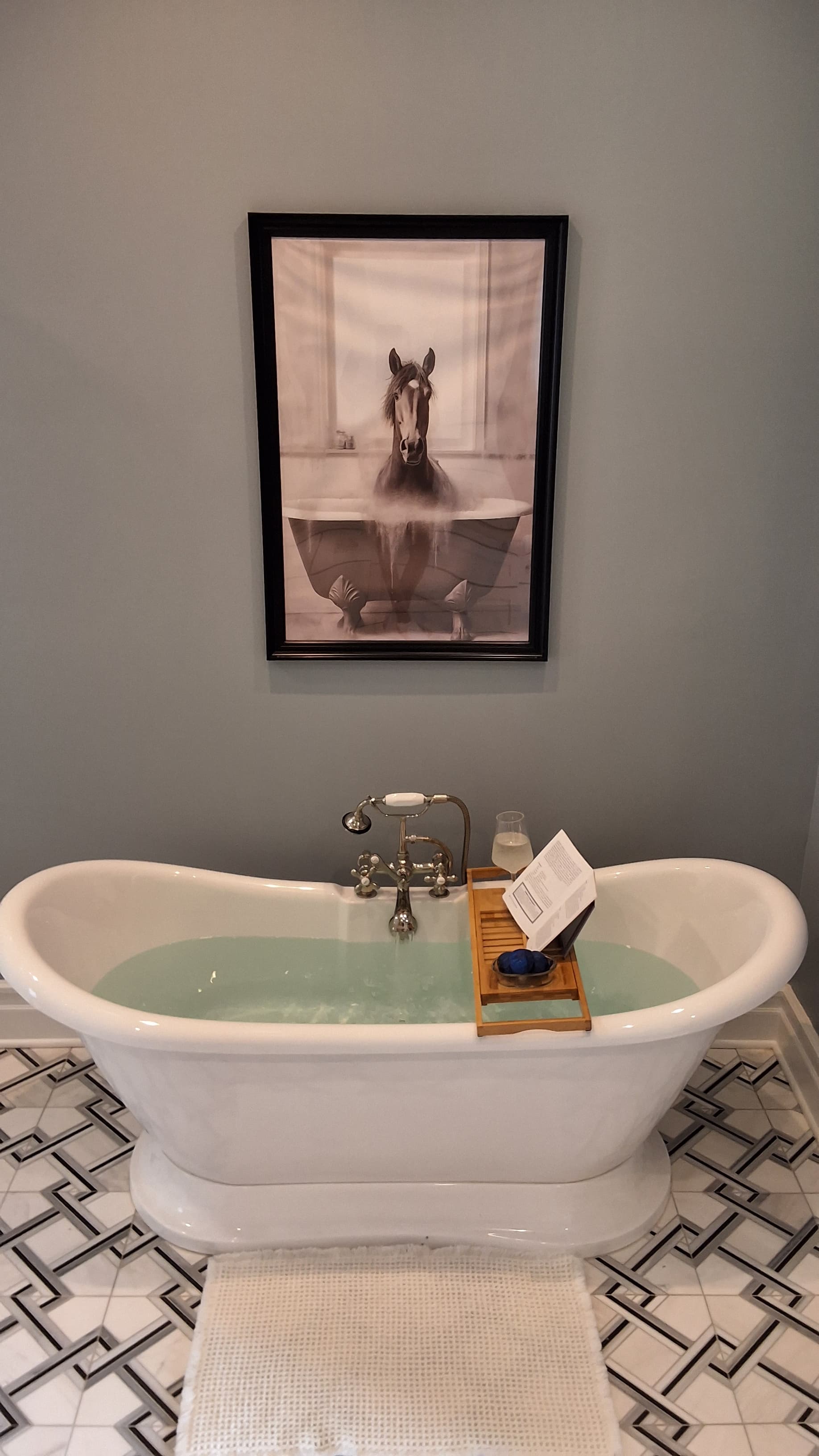 Spa-like bathroom with white slipper soaking tub and beautiful gray and white tiled floor.