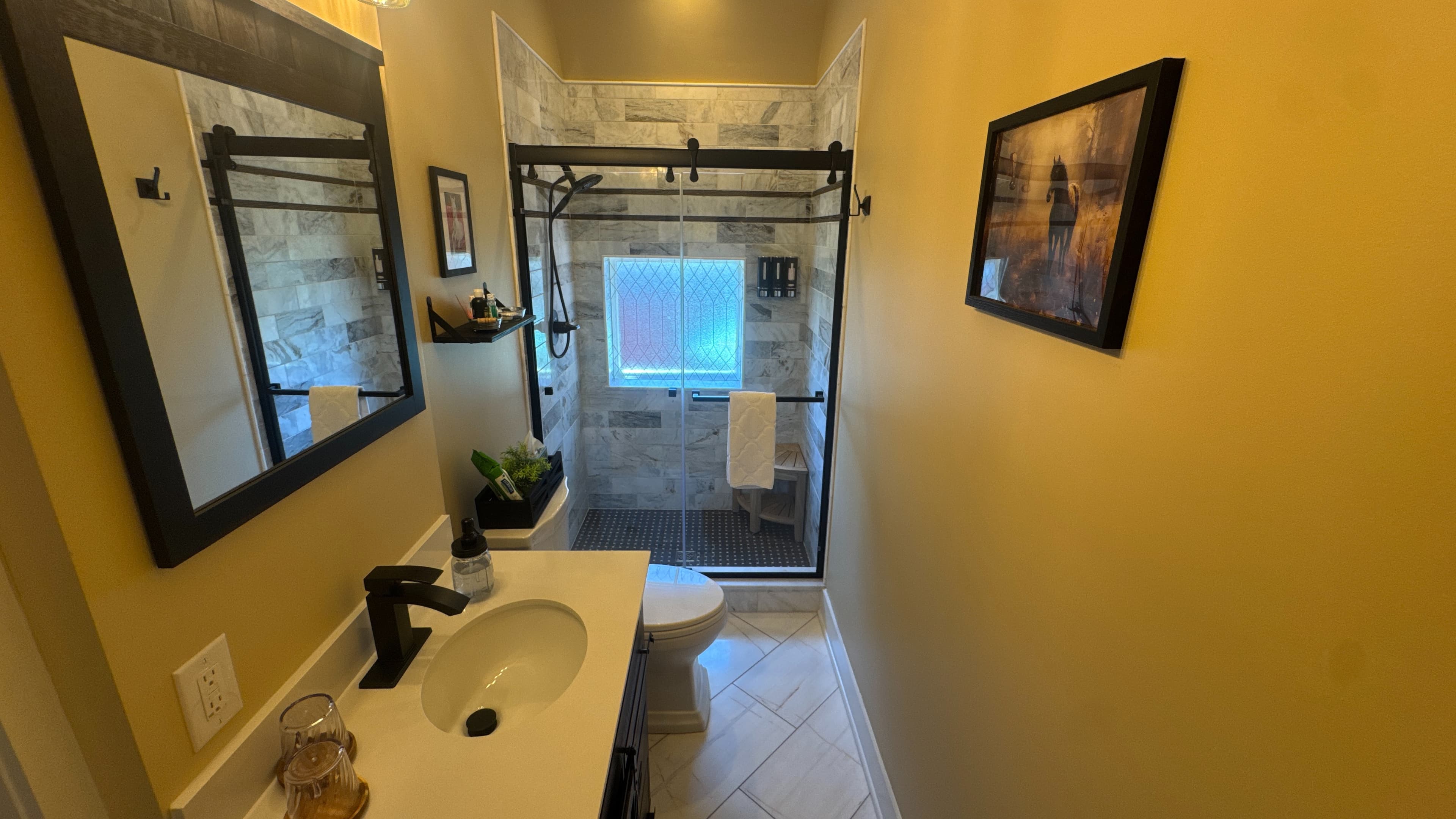 Private bathroom with toilet, sink with vanity, tiled floor, and walk-in shower.