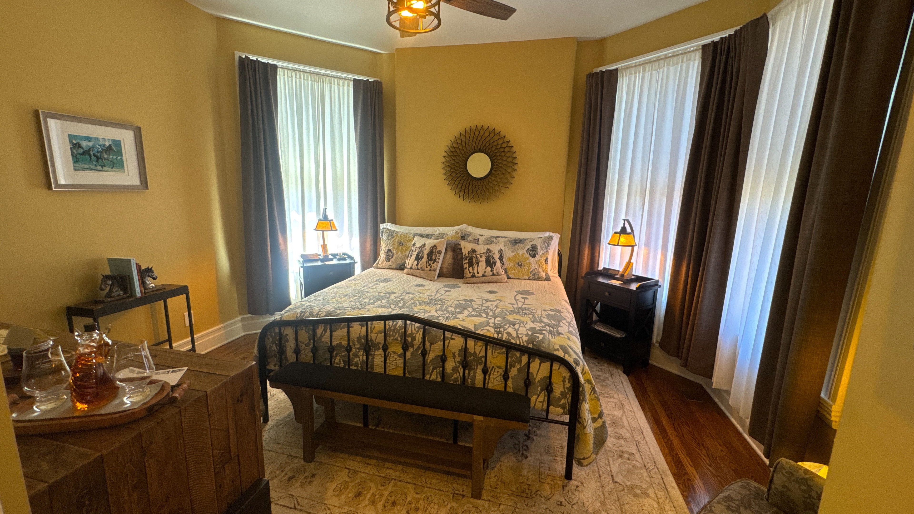 View of the Belmont Suite bedroom revealing a metal king-size bed, hardwood floors, and area rugs.