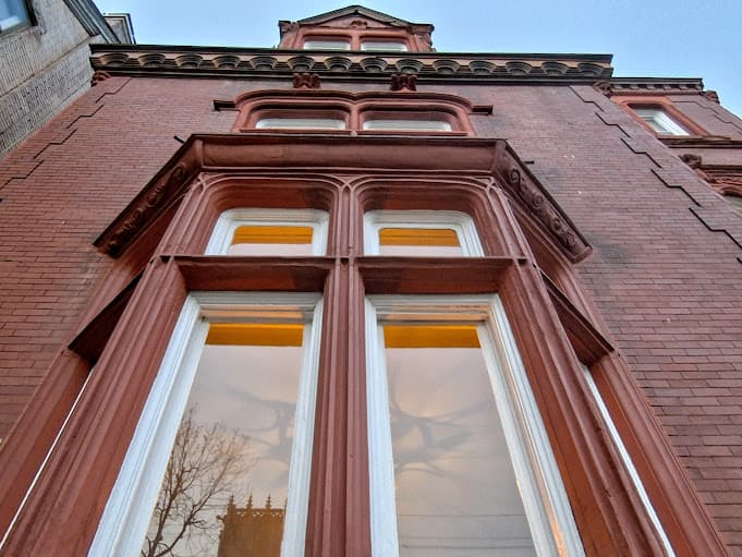 A close-up view of ornate brick architecture featuring large windows with warm lighting.