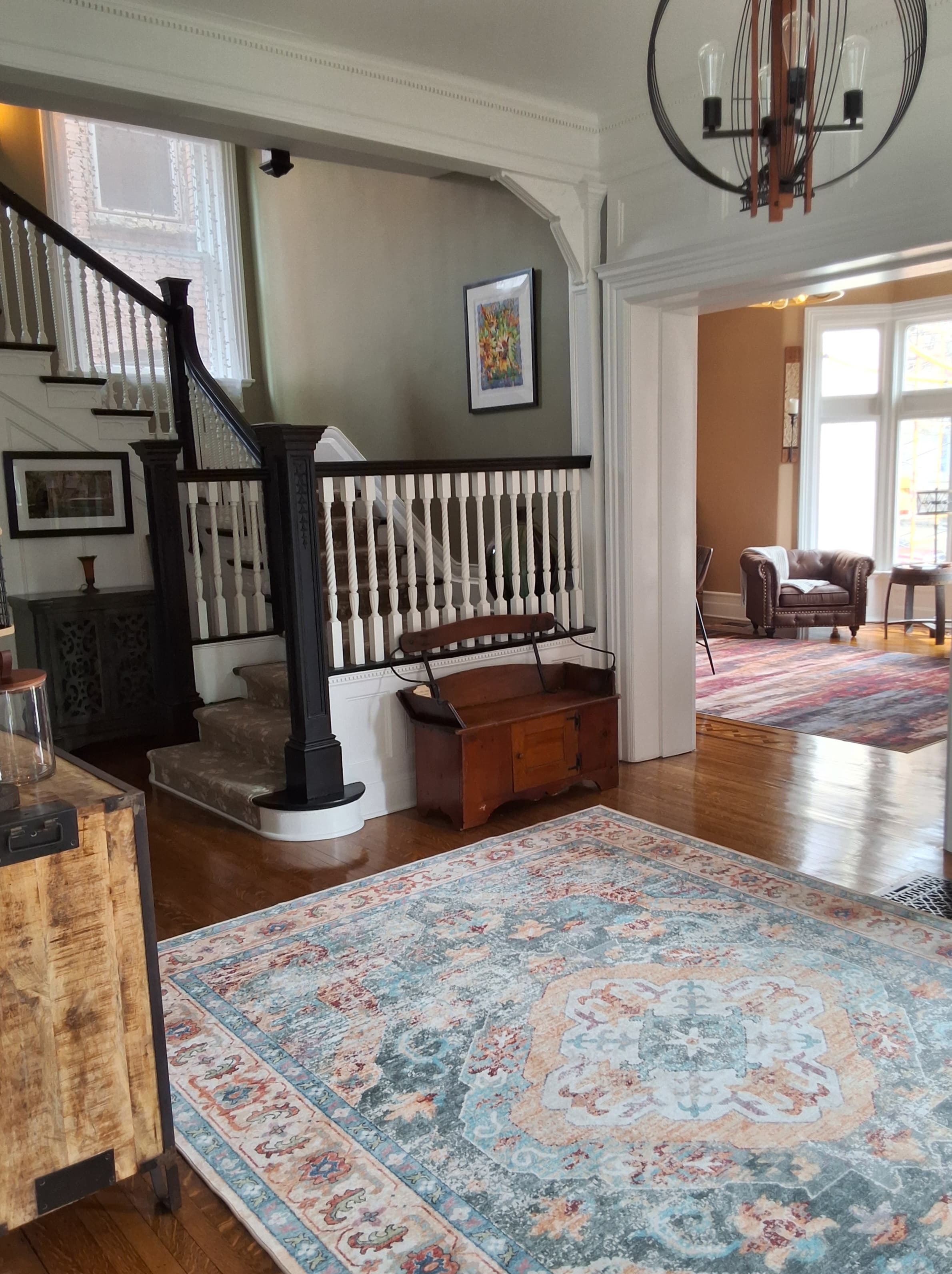 A spacious entryway featuring a staircase, a decorative area rug, and a cozy seating area.