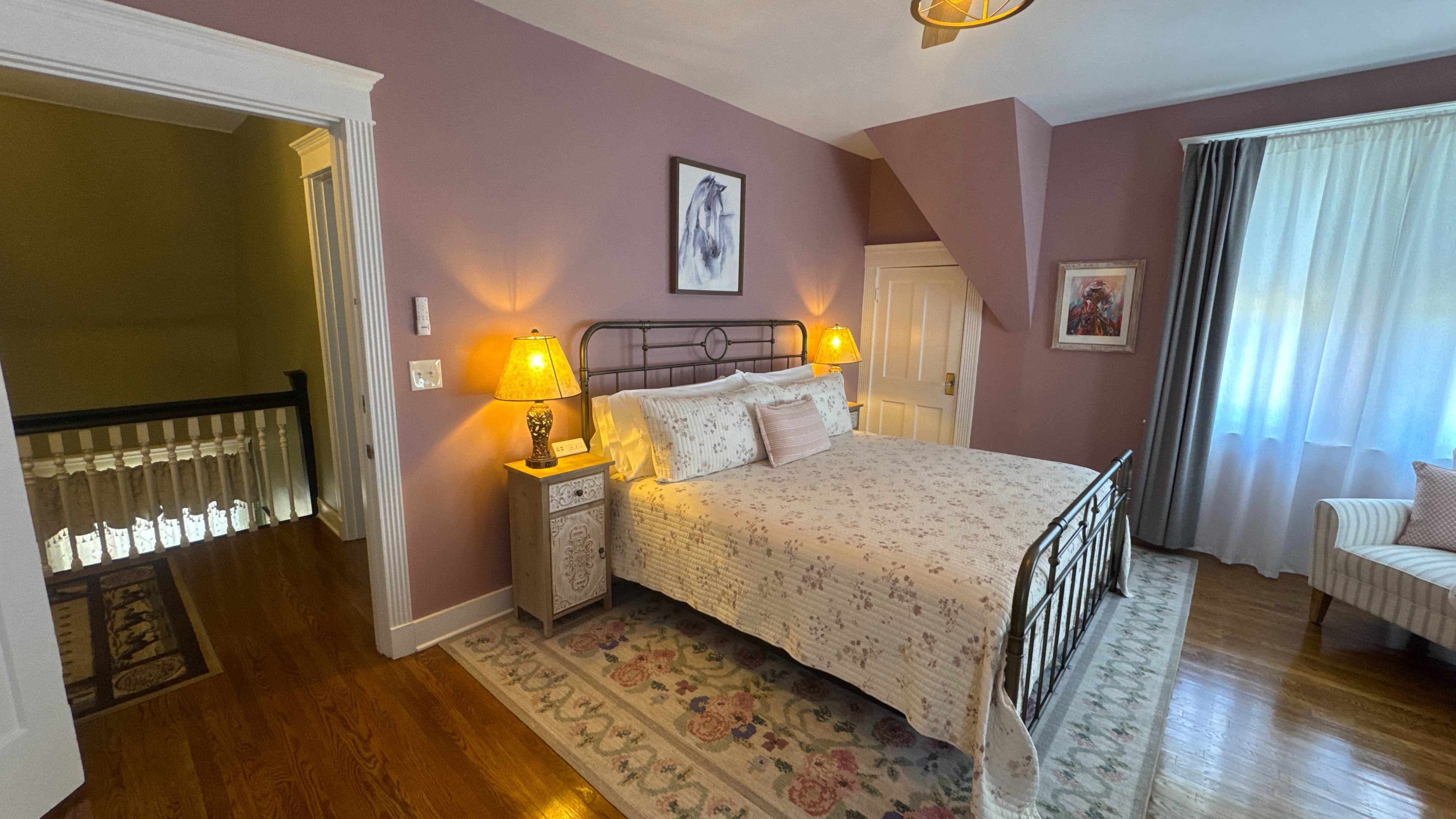Romantic king-size metal bed with white and floral bedspread flanked by nightstands topped with matching lamps.