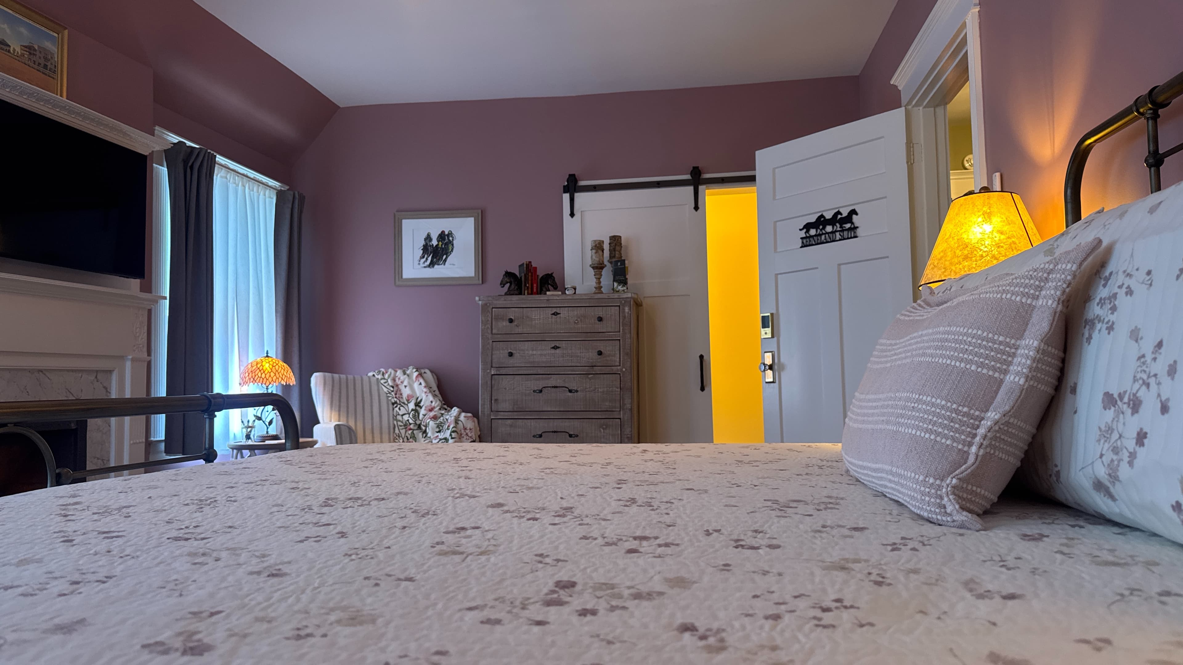 Romantic king-size metal bed with white and floral bedspread flanked by nightstands topped with matching lamps.