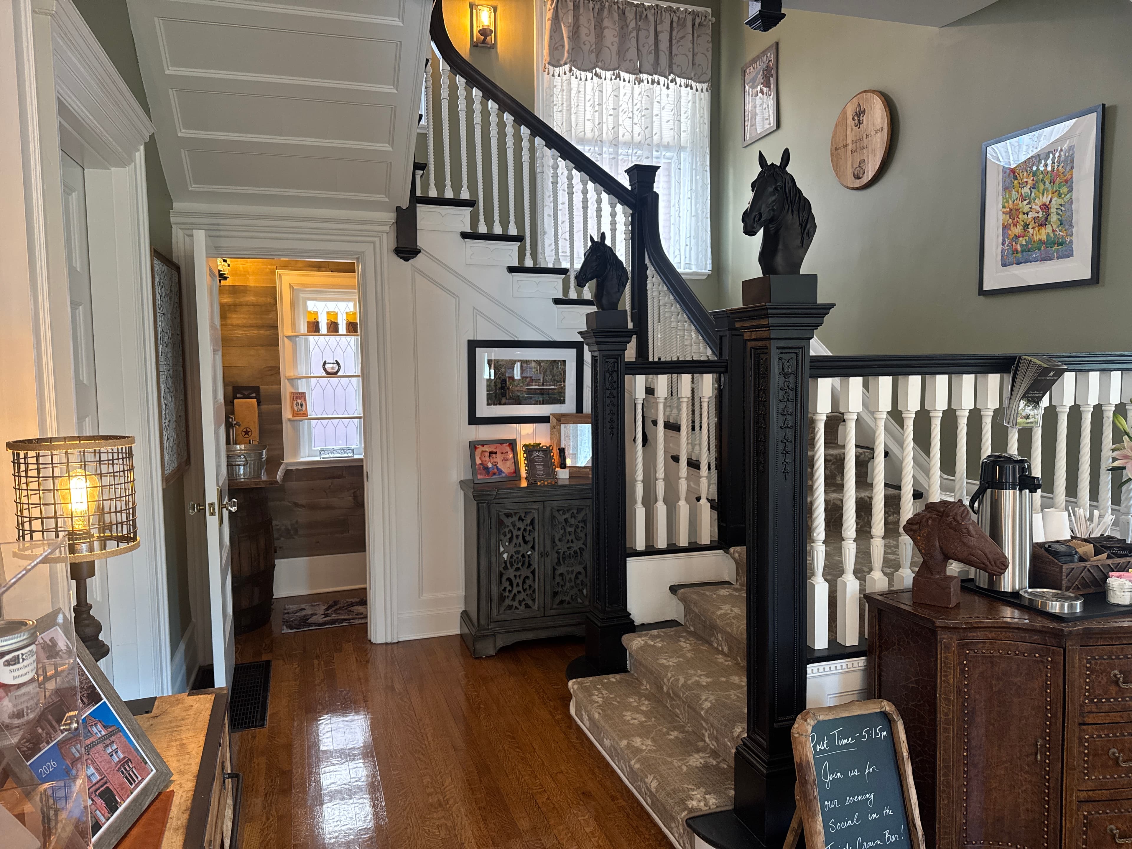 Interior view of a stylish hallway with a staircase, horse figurines, and decorative accents.